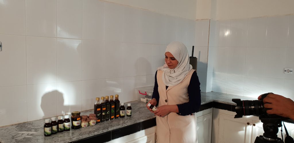 Young Woman displays date palm products, jars and bottles of date vinegar